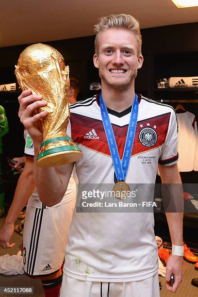 Andre Schuerrle of Germany holds up the World Cup trophy in the Germany dressing room after the 2014 FIFA World Cup Brazil Final match between...
