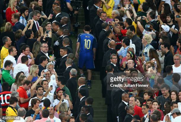 Dejected Lionel Messi of Argentina walks through the fans to receive his Golden Ball trophy after being defeated by Germany 1-0 in extra time during...