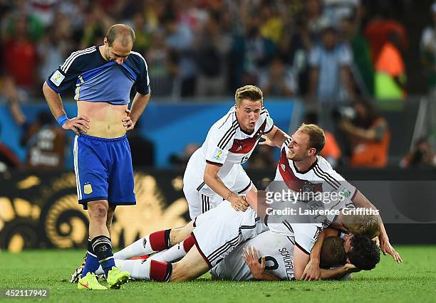 Dejected Pablo Zabaleta of Argentina looks on as Erik Durm, Benedikt Hoewedes, Per Mertesacker and Andre Schuerrle of Germany celebrate their 1-0 win...
