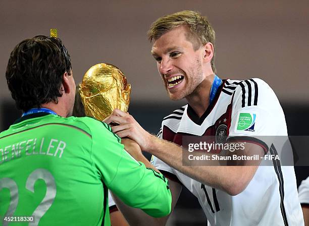 Per Mertesacker of Germany holds the World Cup trophy to celebrate with his teammates during the award ceremony after the 2014 FIFA World Cup Brazil...