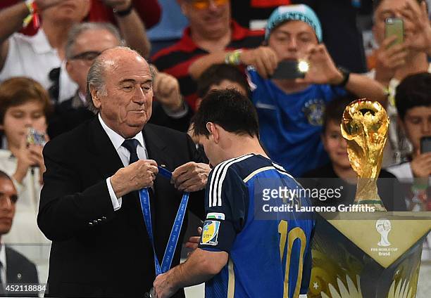 President Joseph S. Blatter presents Lionel Messi of Argentina with his second place medal after being defeated by Germany 1-0 in extra time during...