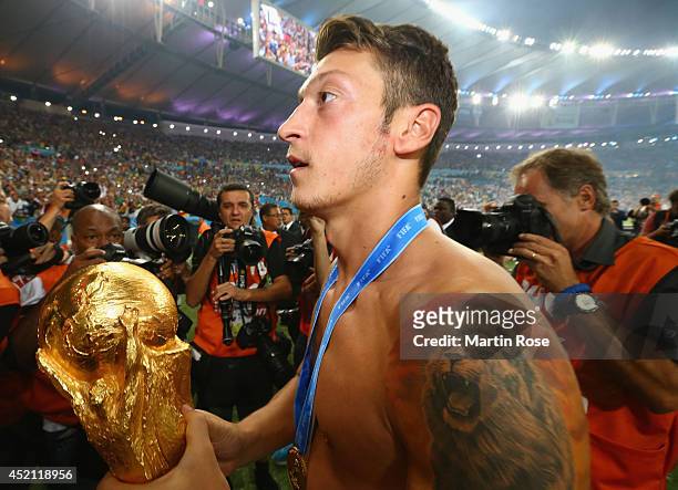 Mesut Oezil of Germany celebrates with the World Cup trophy after defeating Argentina 1-0 in extra time during the 2014 FIFA World Cup Brazil Final...