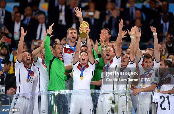 Julian Draxler of Germany lifts the World Cup trophy to celebrate with his teammates during the award ceremony after the 2014 FIFA World Cup Brazil...