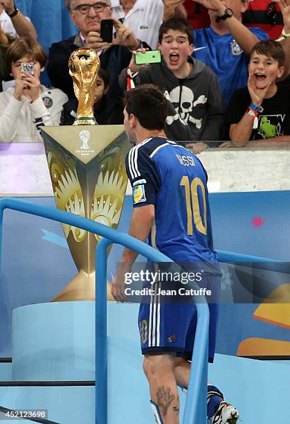 Lionel Messi of Argentina is passing by the trophy after the 2014 FIFA World Cup Brazil Final match between Germany and Argentina at Estadio Maracana...