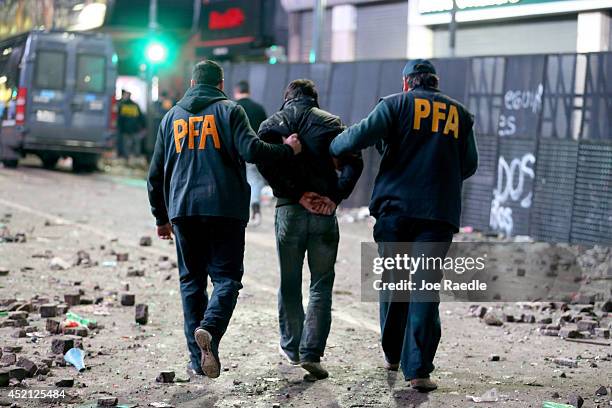 Police officers detain Argentine soccer fans caught after violence erupted near the Obelisco de Buenos Aires after their team lost to Germany 1-0...