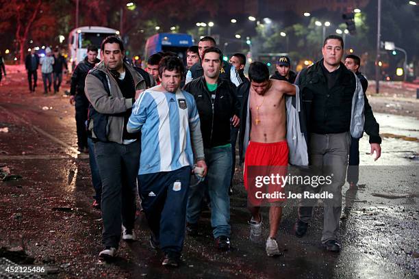 Police officers detain Argentine soccer fans caught after violence erupted near the Obelisco de Buenos Aires after their team lost to Germany 1-0...