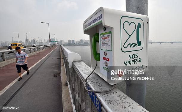 Man walks past an emergency telephone on Mapo Bridge, a common site for suicides, over the Han river in Seoul on July 14, 2014. The suicide rate...