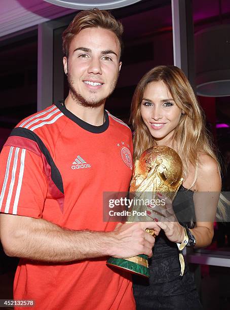 Goalscorer Mario Gotze of Germany and girlfriend Ann-Kathrin Brommel pose with the World Cup trophy as he celebrates with teammates at a party, after...