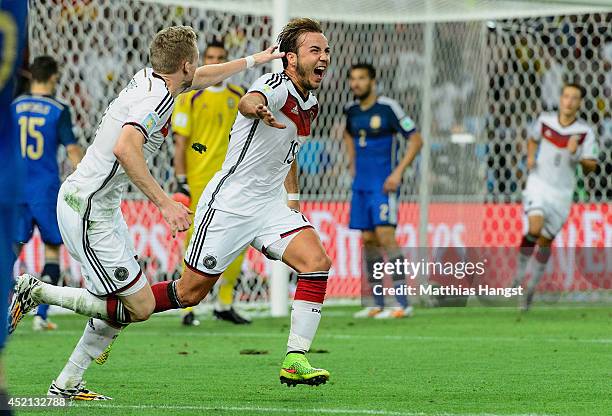 Mario Goetze of Germany celebrates scoring his team's first goal with Andre Schuerrle during the 2014 FIFA World Cup Brazil Final match between...
