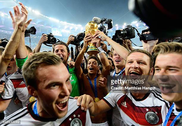 Mesut Oezil of Germany raises the World Cup trophy with teammates Kevin Grosskreutz, Roman Weidenfeller, Shkodran Mustafi and Erik Durm after...