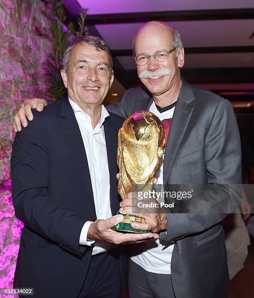 President Wolfgang Niersbach and Chairman of Daimler AG Dieter Zetsche pose with the World Cup trophy as they celebrate at a party, after winning the...