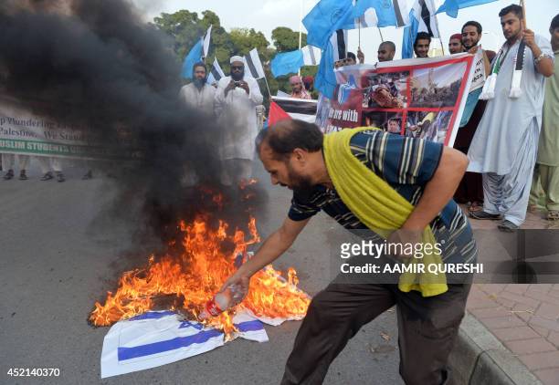 An activist of Muslim Students Organization Pakistan torches Israeli and US flags during a demonstration against Israeli military operations in Gaza,...