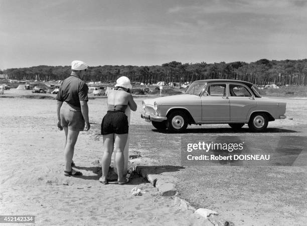 Couple taking a photo of their car during their holidays,1960 in France.