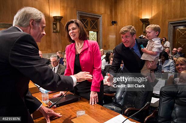 From left, Chairman Tom Carper, D-Del., greets Vicky Kennedy at the witness table as former Rep. Patrick Kennedy, D-R.I., stands with his son Owen...