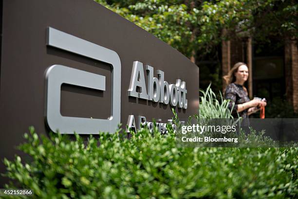 An employee walks near an Abbott Laboratories sign at the company's headquarters complex in Abbott Park, Illinois, U.S., on Monday, July 14, 2014....