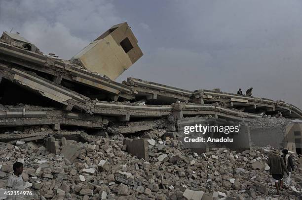 Yemenis stand on the wreckage of a building destroyed by Houthi rebels in fighting between Yemeni army forces and Houthi rebels in Amran, north of...