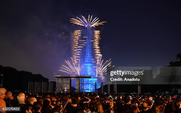 People watch and take photo of firework show fired from the Eiffel Tower for French National Day , France on 14 July, 2014.