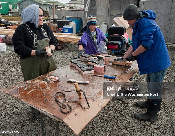 Dora Brower cuts up muktuk with her nephews in her yard in Barrow The whale had been caught in the fall and had been seasoning over the winter in...