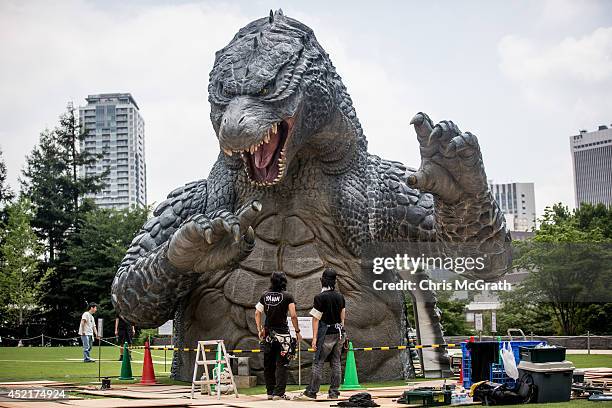 Crewmember Tetsuo Hayashi airbrushes the final touches to a 6.6 meter replica of the famous Godzilla at Tokyo Midtown on July 15, 2014 in Tokyo,...