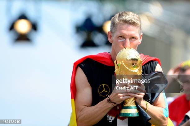 Germany's national football team's midfielder Bastian Schweinsteiger kisses the trophy as he celebrates their FIFA World Cup 2014 title at a victory...