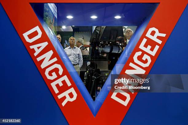 Visitors are seen through a 'Danger' warning sign as they look at an ejector seat used in the Lockheed Martin Corp. F-35 Lightning II joint strike...