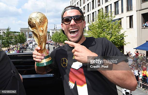 Lukas Podolski celebrates on the open top bus at the German team victory ceremony on July 15, 2014 in Berlin, Germany. Germany won the 2014 FIFA...