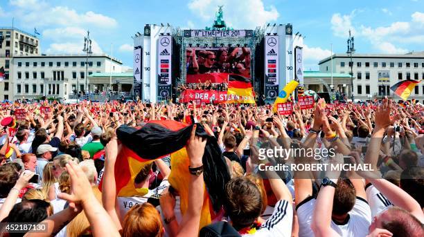 Germany's national football team playes and team members are displayed on a giant screen as hundreds of thousands of football fans gather at the...