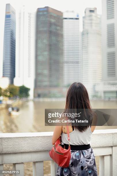 woman looking at singapore skyline - singapore river stock-fotos und bilder