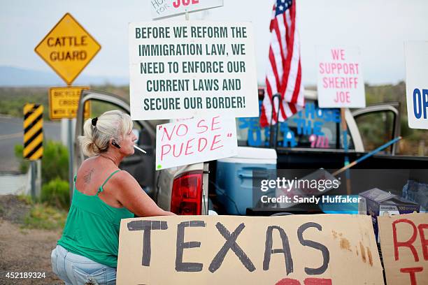 Anti-immigration activist Barb Heller sets up signs on her truck during a protest along Mt. Lemmon Road in anticipation of buses carrying illegal...