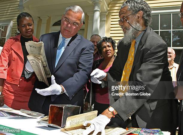 Outside the Roxbury Historical Society building this morning Mayor Tom Menino, left, assisted in unveiling the contents of a 1922 time capsule that...