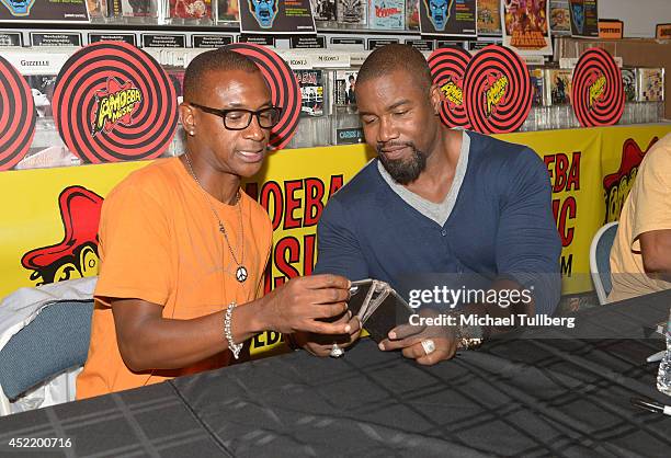 Actor Tommy Davidson and producer Michael Jai White look at a cel phone at a signing for the new DVD "Black Dynamite" at Amoeba Music on July 15,...