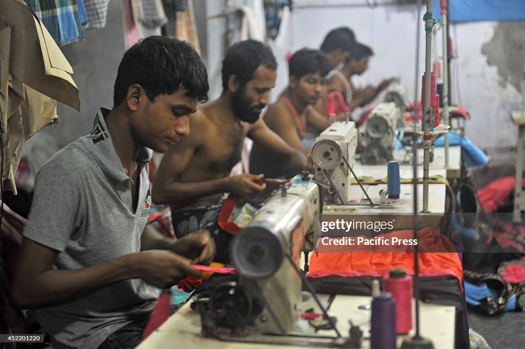 Bangladeshi garment workers sewing clothes in a factory for...