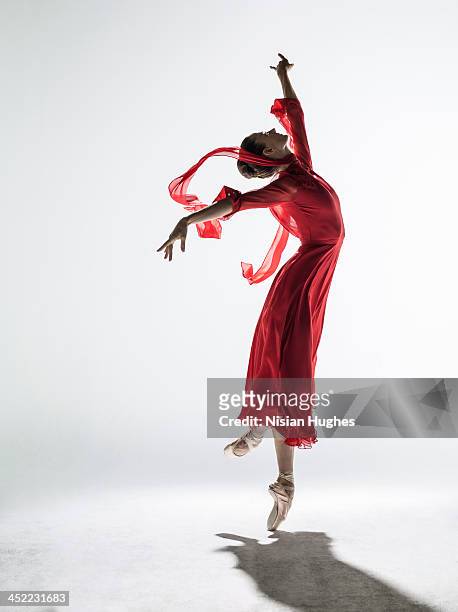 ballerina performing coupe derriere en pointe - red dress stock pictures, royalty-free photos & images