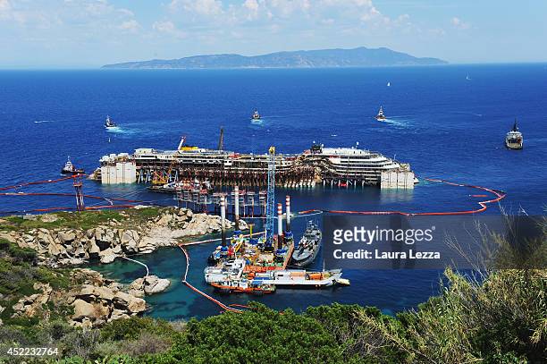View of the wrecked ship Costa Concordia and the tugs is seen after the first stage of refloating operations on July 16, 2014 in Isola del Giglio,...