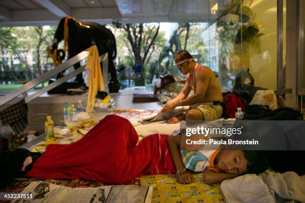 Young child rests next to her family as anti-government protesters occupy the Finance ministry for a third day in a bid to oust the current...