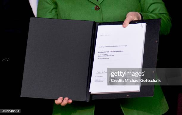 German Chancellor and Chairwoman of the German Christian Democrats Angela Merkel, holds the three parties' coalition contract on November 27, 2013 in...