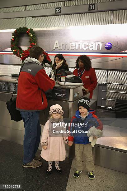 Rosalie and Vincent McCormick wait as their father Kevin checks in for a flight at O'Hare International Airport on November 27, 2013 in Chicago,...