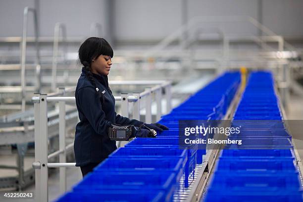 An employee sorts empty plastic crates on a conveyor belt at a Tesco Plc on-line distribution center, in Erith, U.K., on Wednesday, Nov. 27, 2013....