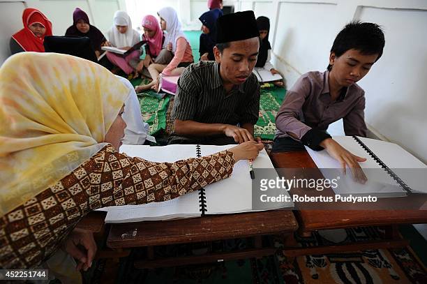 Teacher speaks to visually impaired students as they read the Braille Quran at The Foundation for The Education of Blind Children on July 17, 2014 in...