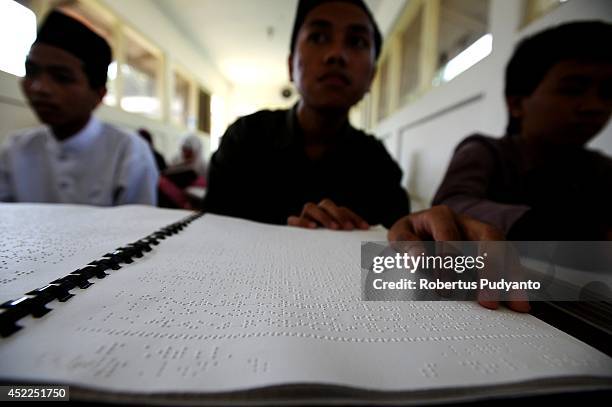 Visually impaired students read a Braille Quran at The Foundation for The Education of Blind Children during Ramadan on July 17, 2014 in Surabaya,...