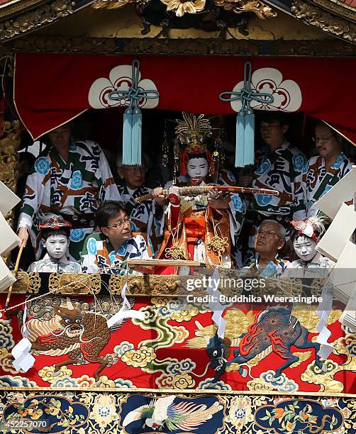 Sacred child hold sword as performs a ritual on a float named Yamahoko before the cuts a Shimenawa, sacred wire rope during the annual Kyoto Gion...