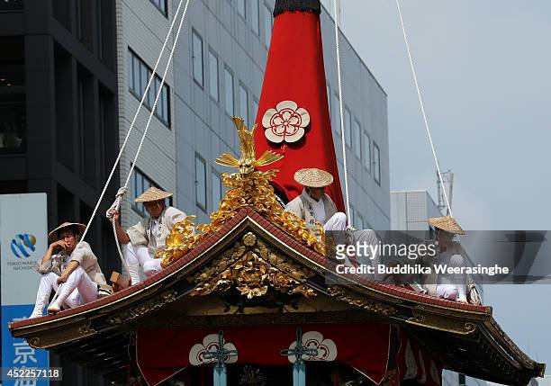 Japanese men dressed in traditional costumes sit on the roof top of festival cart named Yamahoko during the annual Kyoto Gion Festival on July 17,...