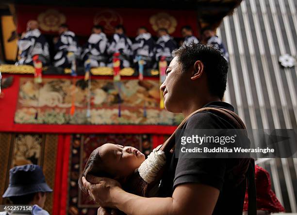 Japanese man holds his sleeping baby and looks floats parade during the annual Kyoto Gion Festival on July 17, 2014 in Kyoto, Japan. The Gion...