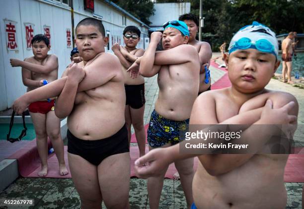 Overweight Chinese students stretch after swimming during training at a camp held for overweight children on July 15, 2014 in Beijing, China. Obesity...