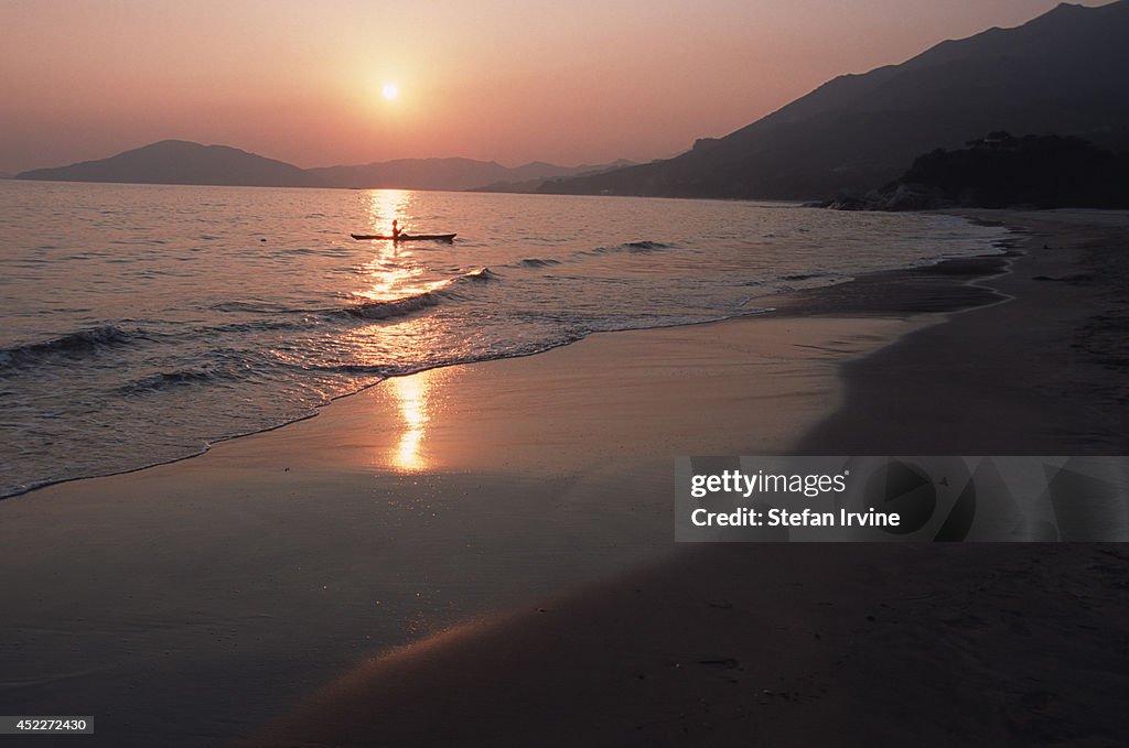 A lone kayaker paddling at sunset...