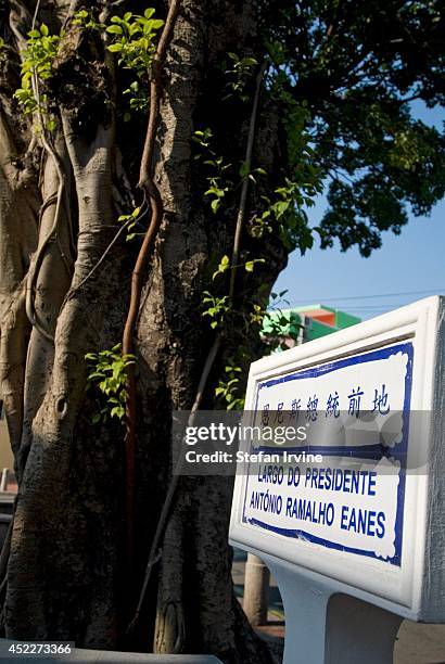 Typical street sign in Coloane village, Macau, shows the place name in Chinese and Portuguese, painted in blue on white tiles.