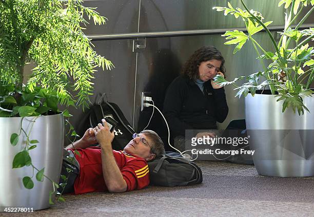 Holiday travelers lay and sit on the floor as they wait for their flights at the Salt Lake City international Airport on November 27, 2013 in Salt...