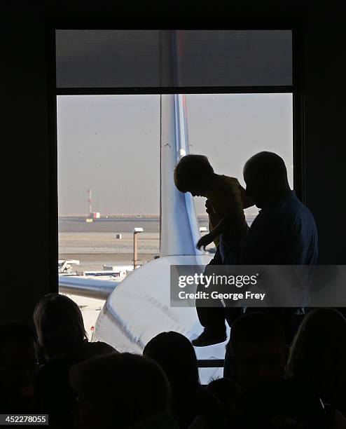 Man picks up a child as they wait to board a plane the Salt Lake City international Airport on November 27, 2013 in Salt Lake City, Utah. A wintry...