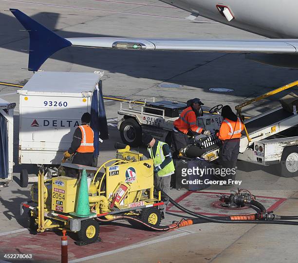Baggage handlers load and unload a Delta plane at the Salt Lake City international Airport on November 27, 2013 in Salt Lake City, Utah. A wintry...