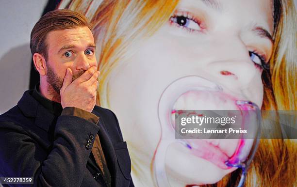 Artist Niels Ruf poses during his photography exhibition "Bitte recht freundlich" in front of a photograph of model Eva Padberg on November 27, 2013...